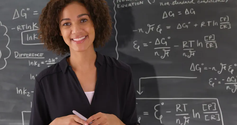 Portrait of black teacher giving math lesson on chalkboard