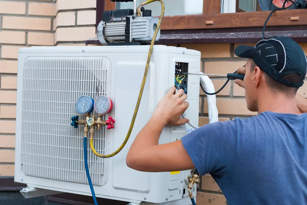 the worker installs the outdoor unit of the air conditioner on the wall of the house