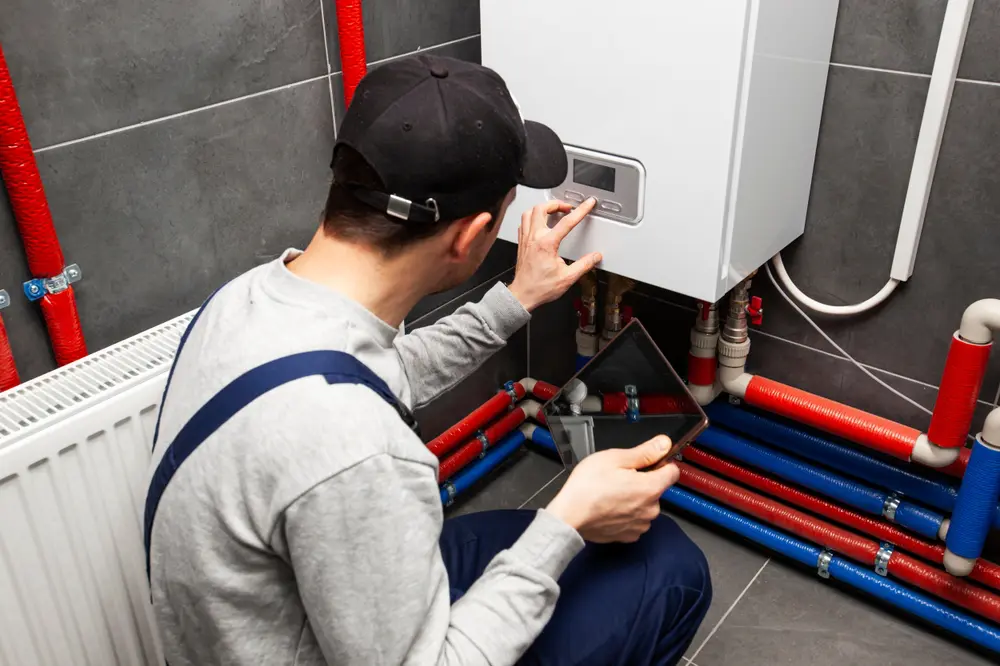 The technician checking the heating system in the boiler room with tablet in hand