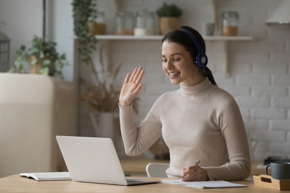 Young woman in headphones start online class, greets tutor feels happy enjoy effective e-learn, use video call and laptop. Video conference for study, easy, comfort modern tech usage. Tuition