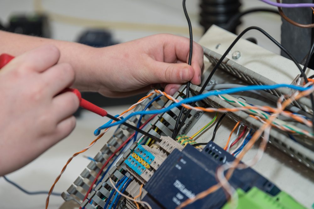 Electrical engineer works with screwdriver on installations in the workplace