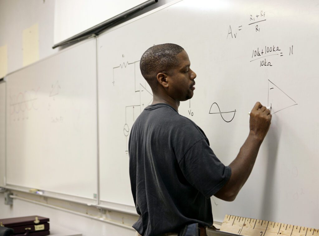 A handsome african-american student doing trigonometry at the board.